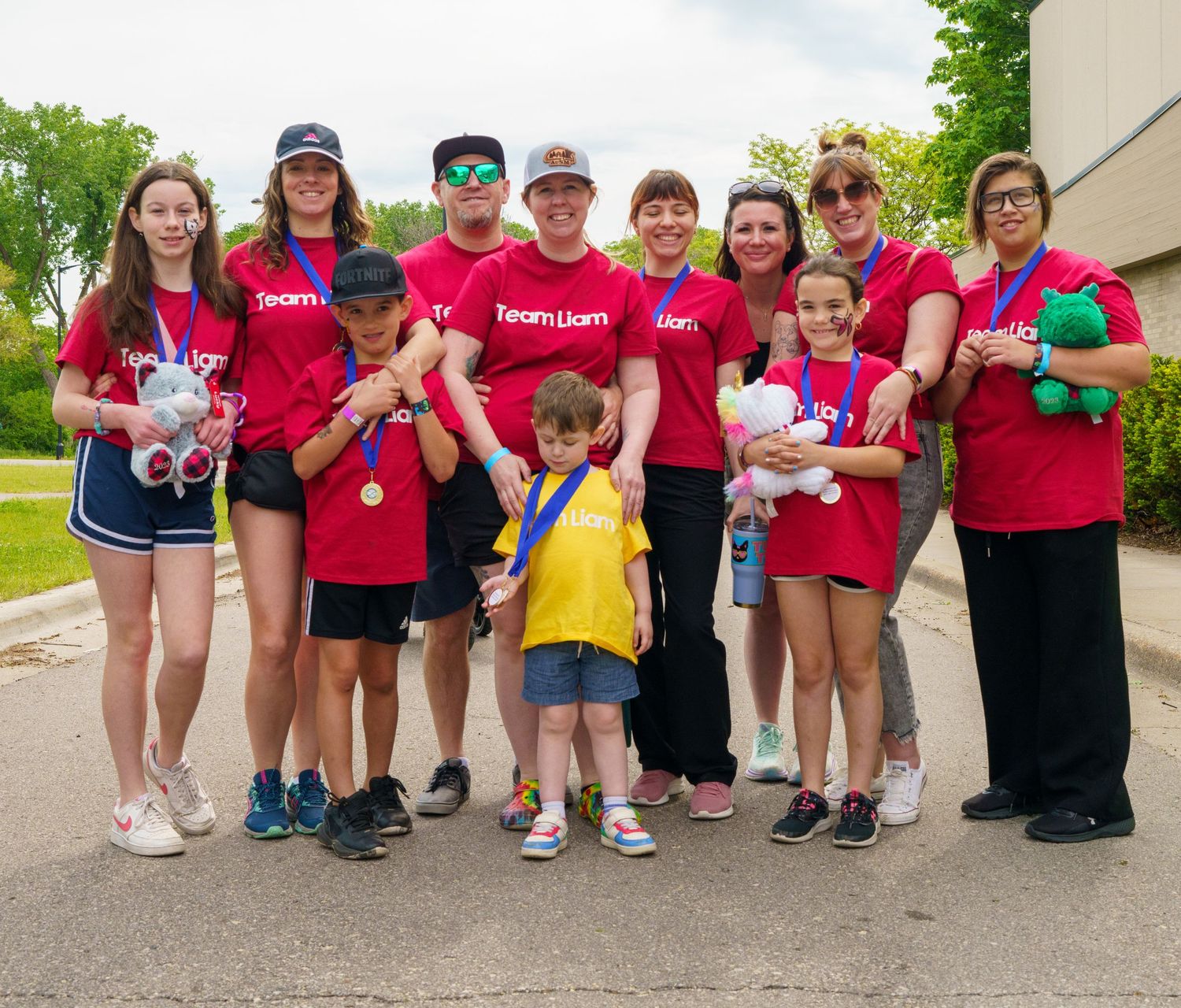 Group photo of volunteers in red shirts at community event outdoors.