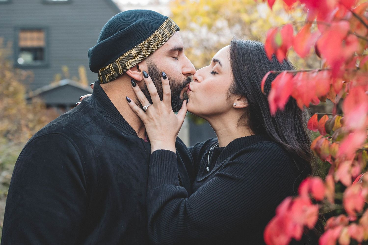 A couple shares an intimate moment among autumn foliage.
