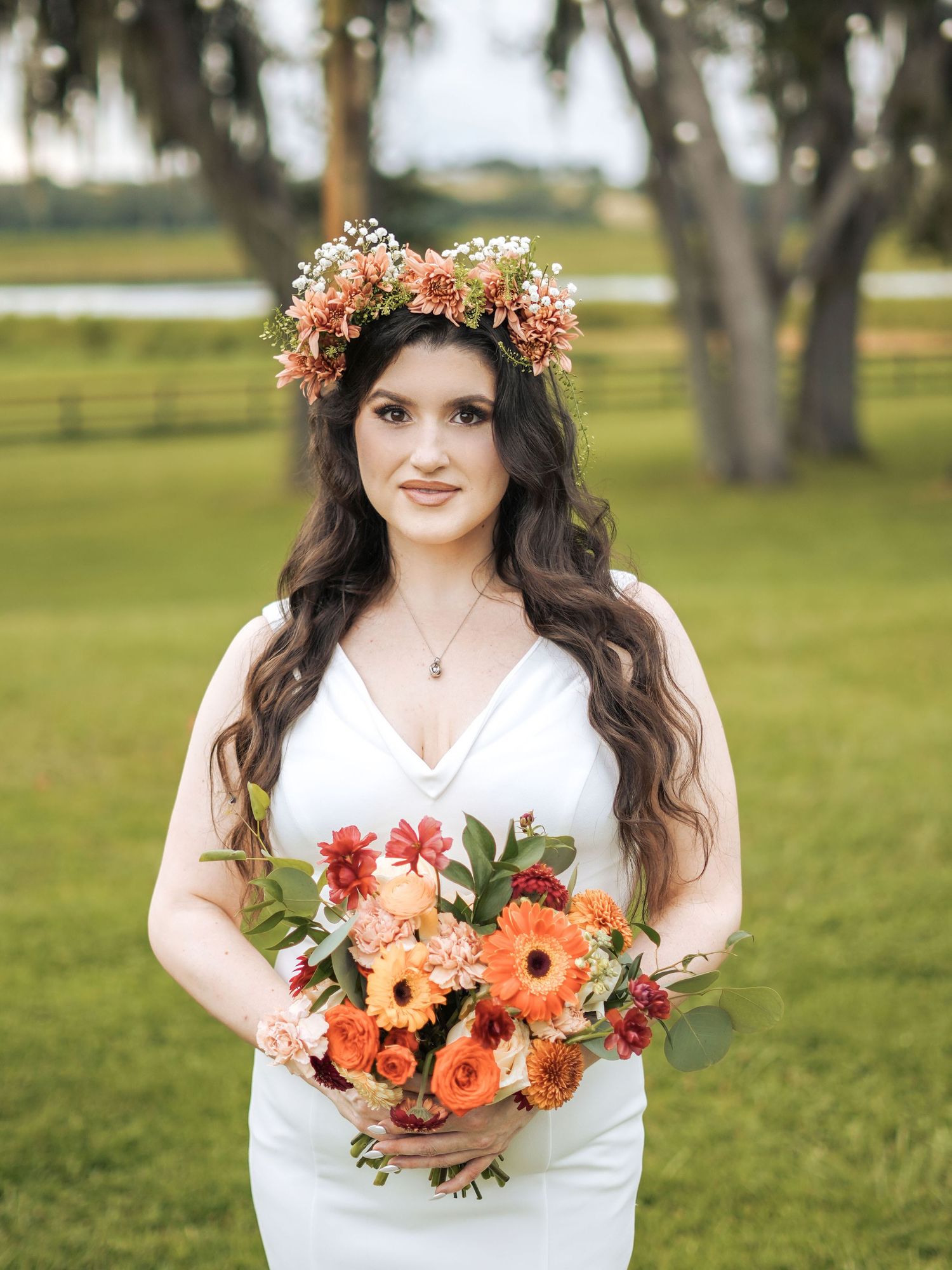 Bridal portrait showcasing coral flower crown and matching bouquet against a serene garden backdrop.