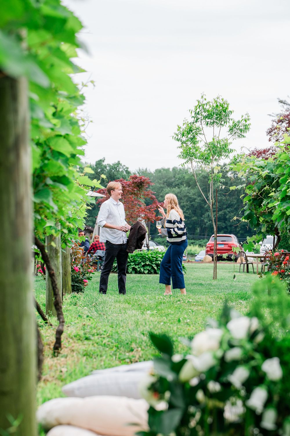 couple gather in a lovely vineyard setting with lush greenery and white flowers framing the natural outdoor scene.
