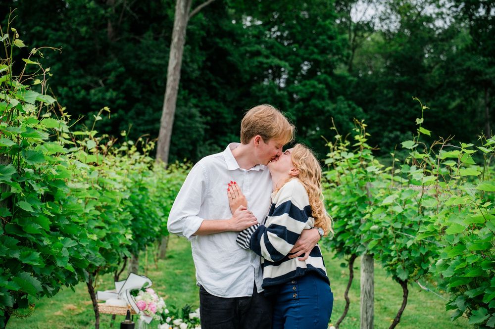 A couple sharing an intimate moment while dancing together outdoors among green foliage and trees.