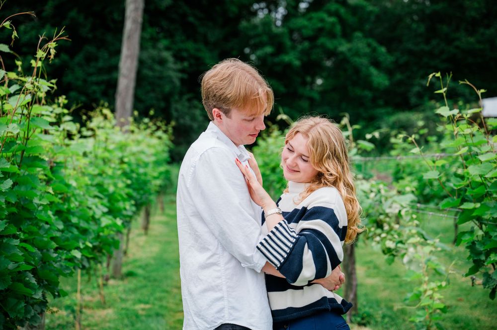 Two young children embrace while standing outdoors in a lush green garden setting.