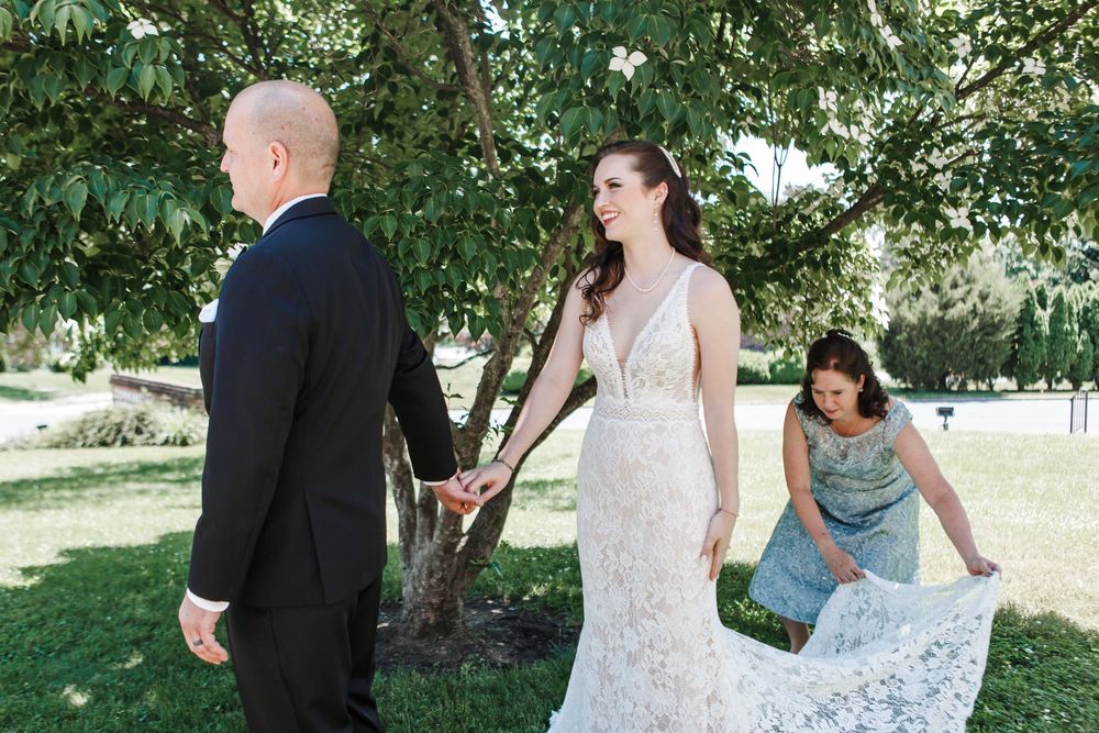 Couple shares a romantic moment in a sunlit garden setting with flowering trees and greenery.