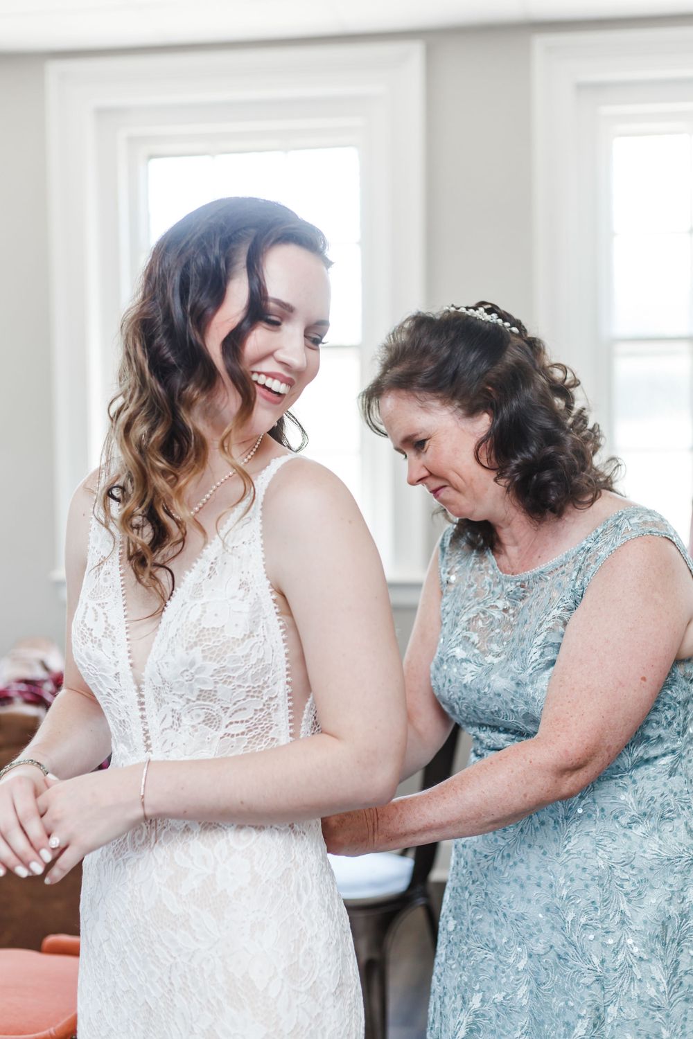 Emotional moments between a bride in a lace wedding dress and her loved one wearing a sparkly blue dress.