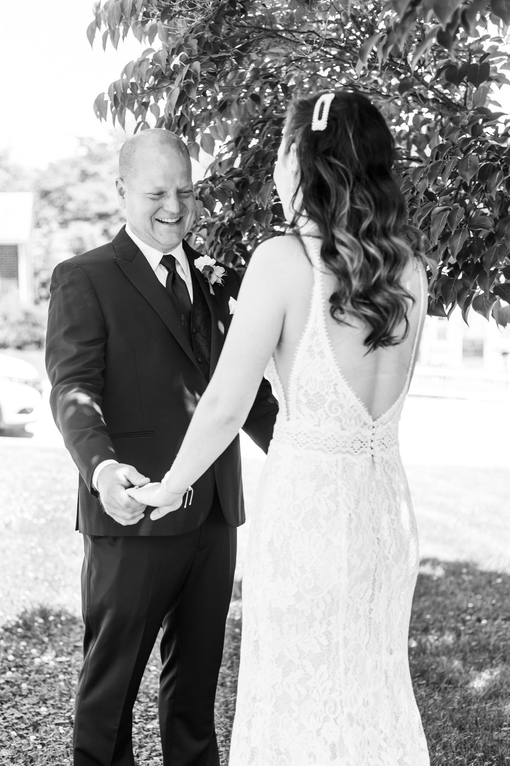 A romantic first look between bride and groom on their wedding day with him wearing black suit and her in white gown.