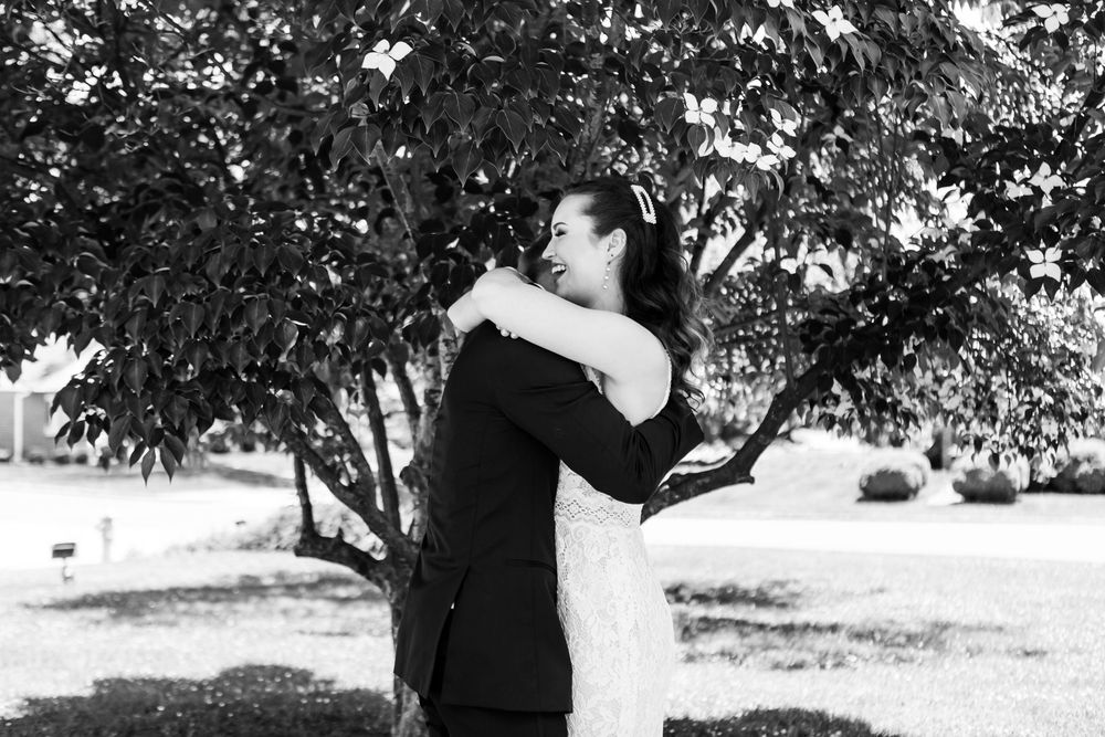 Black and white photo of newlyweds sharing a tender moment in a garden setting.