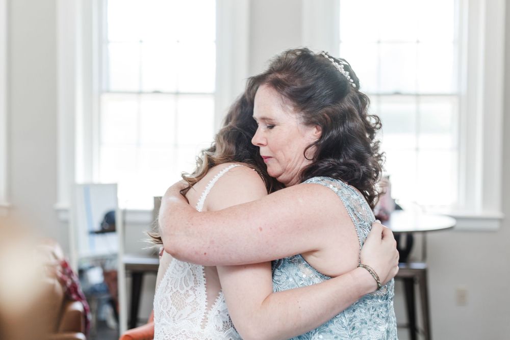 Emotional wedding day moments captured with embraces and joyful interactions near sunlit windows.