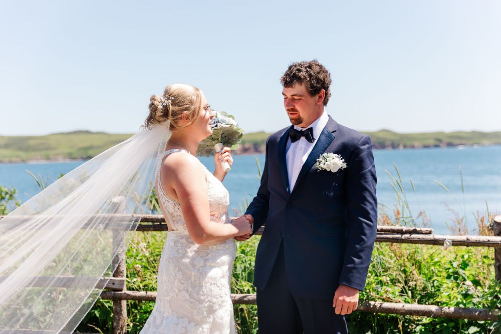 A couple shares a joyful moment on their wedding day overlooking a scenic waterfront landscape.