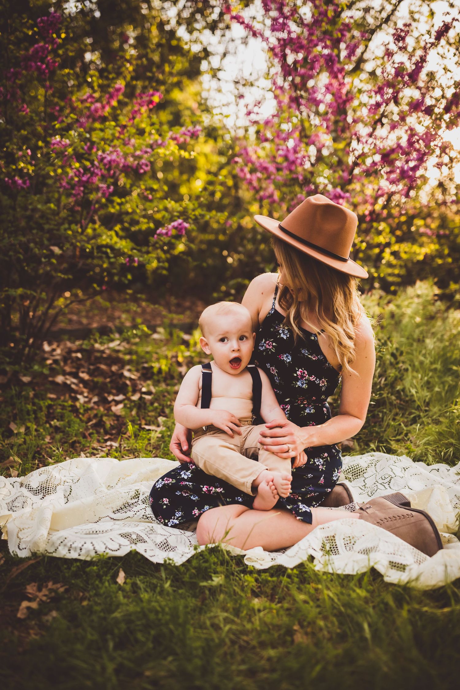 A springtime family photoshoot on a white blanket surrounded by blooming cherry blossoms.