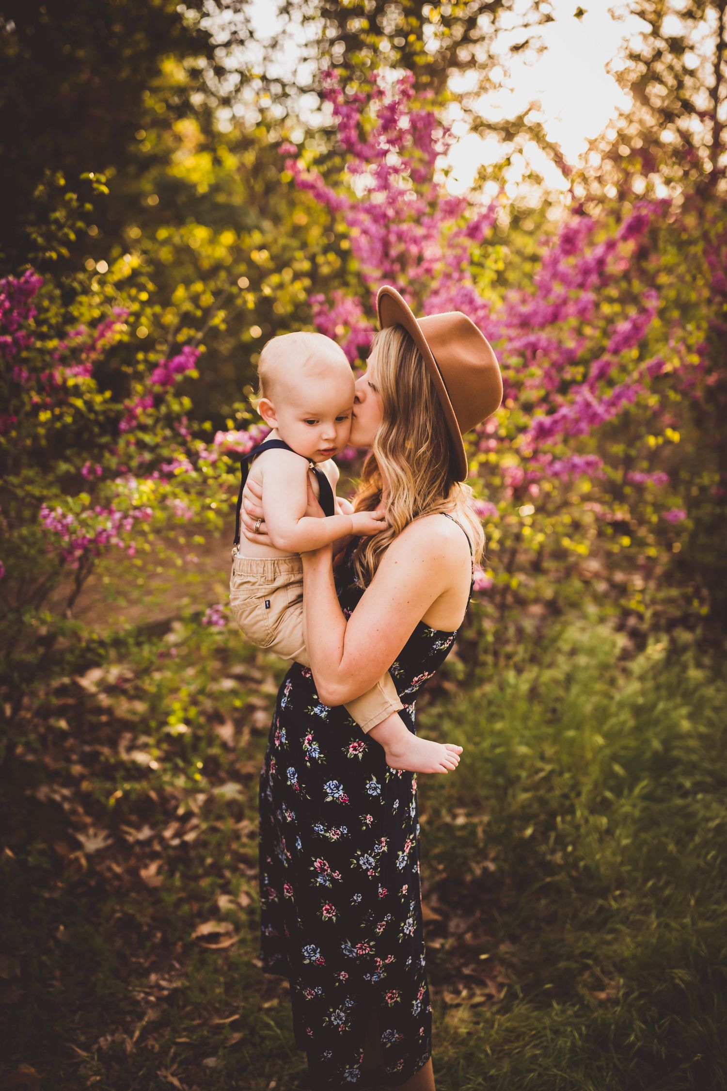 Beautiful spring portrait against blooming pink flowers in warm evening light.