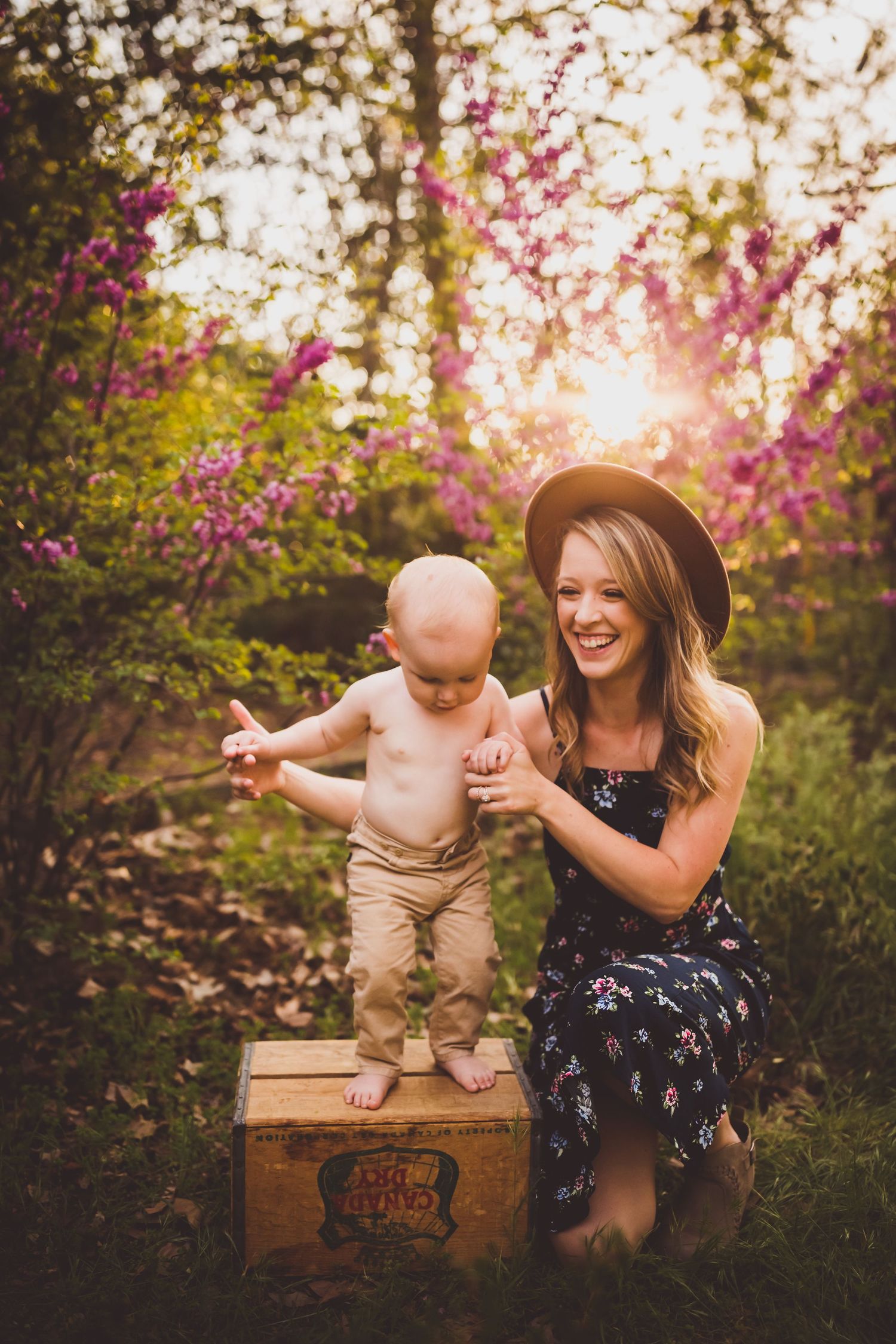 A playful moment captured at sunset with blooming trees and a wooden crate as props.