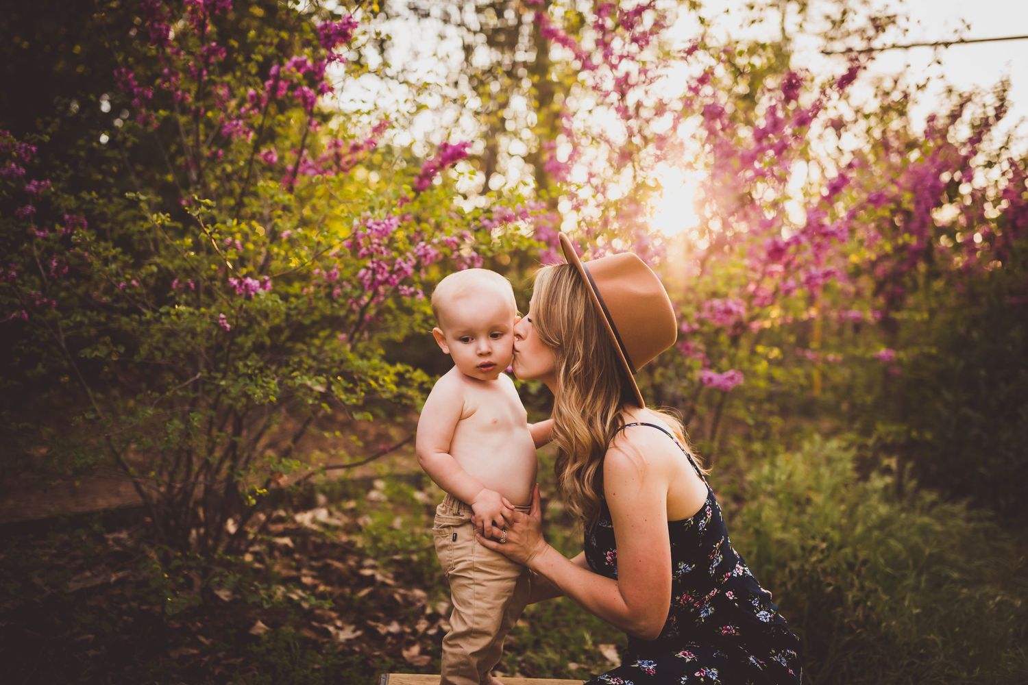 A sweet moment captured during golden hour with pink cherry blossoms in the background.