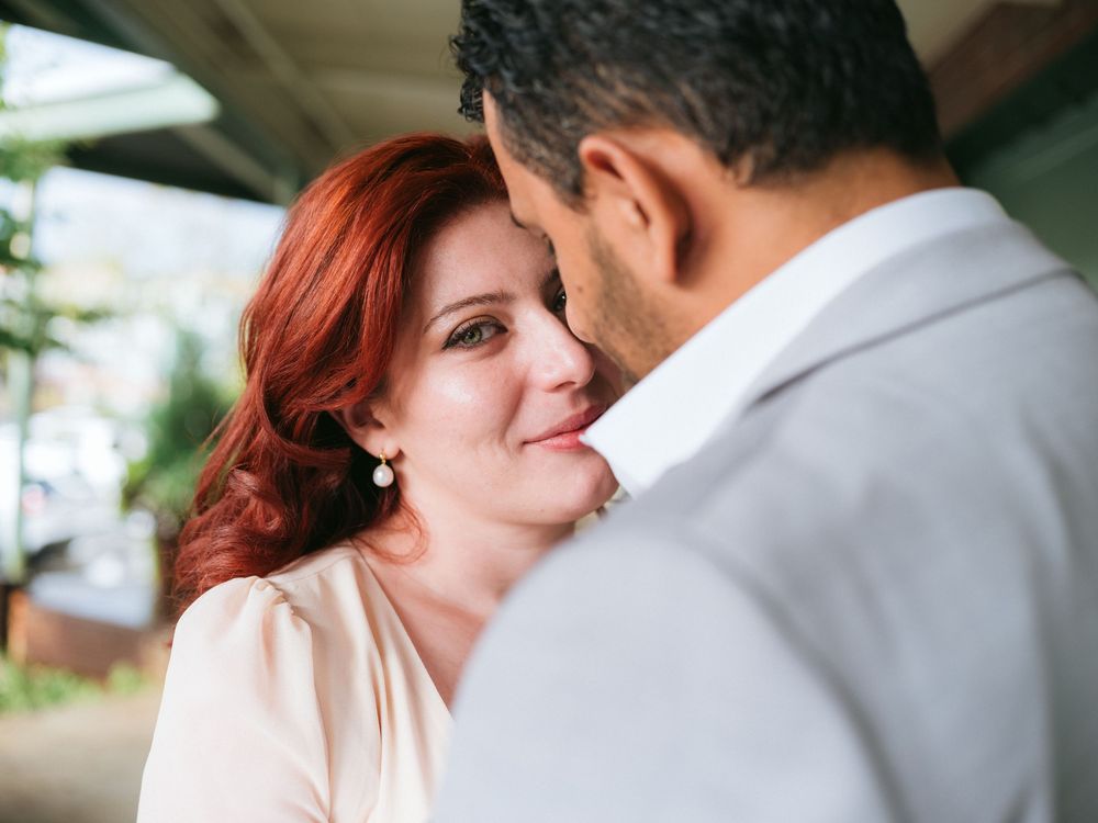 Close up romantic moment between couple with woman in pink top smiling at partner in white dress shirt.