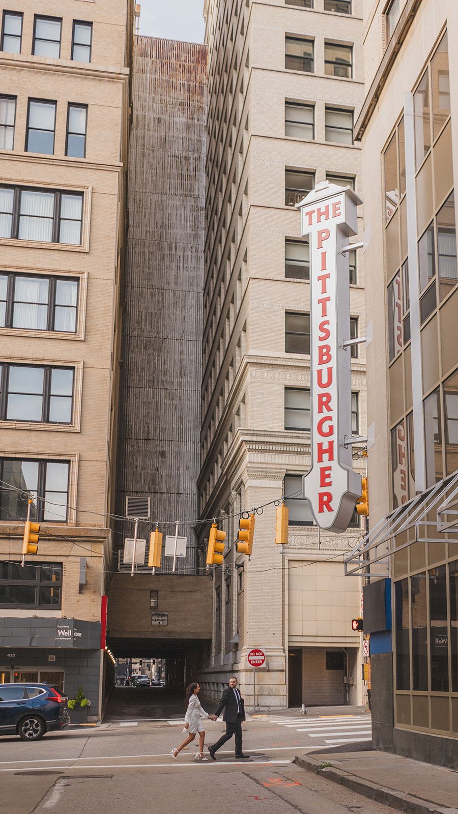 Urban street scene in Pittsburgh with tall beige building and vertical street banners visible.