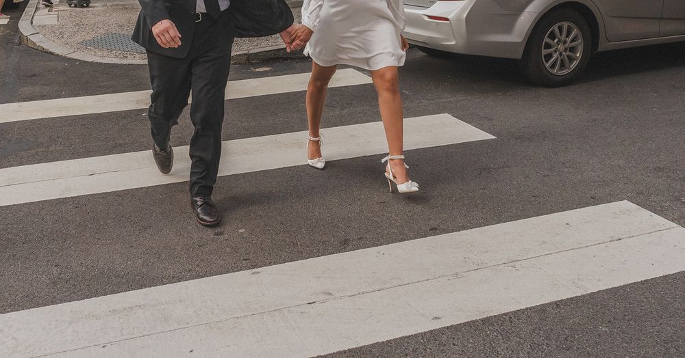 Close-up view of feet walking across an urban crosswalk on a city street.