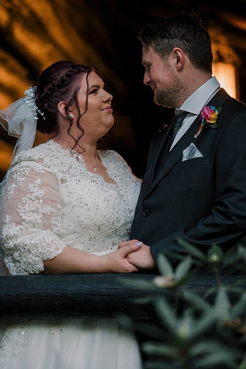 Romantic wedding couple share an intimate moment together in a dimly lit venue with orange ambient lighting in background.