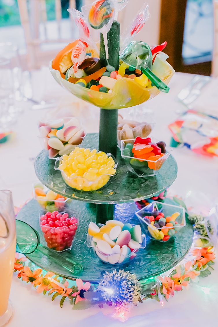 Colorful dessert display with tiered stand featuring fruits, candies and decorative treats.