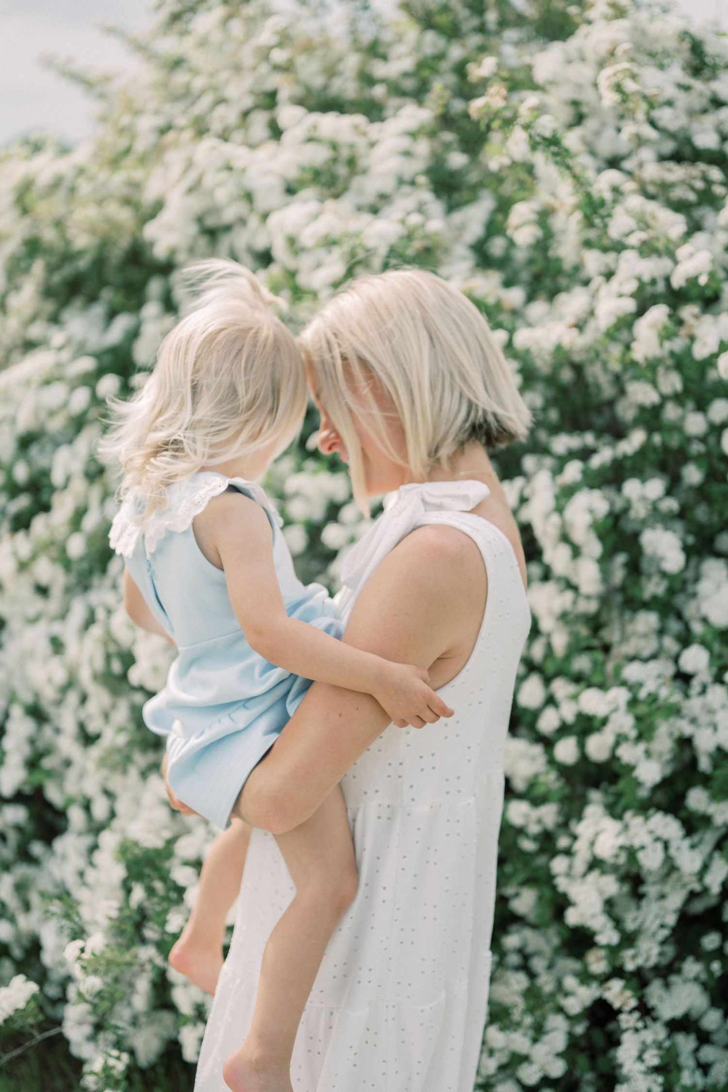 Tender moment captured against flowering bush background in soft light.