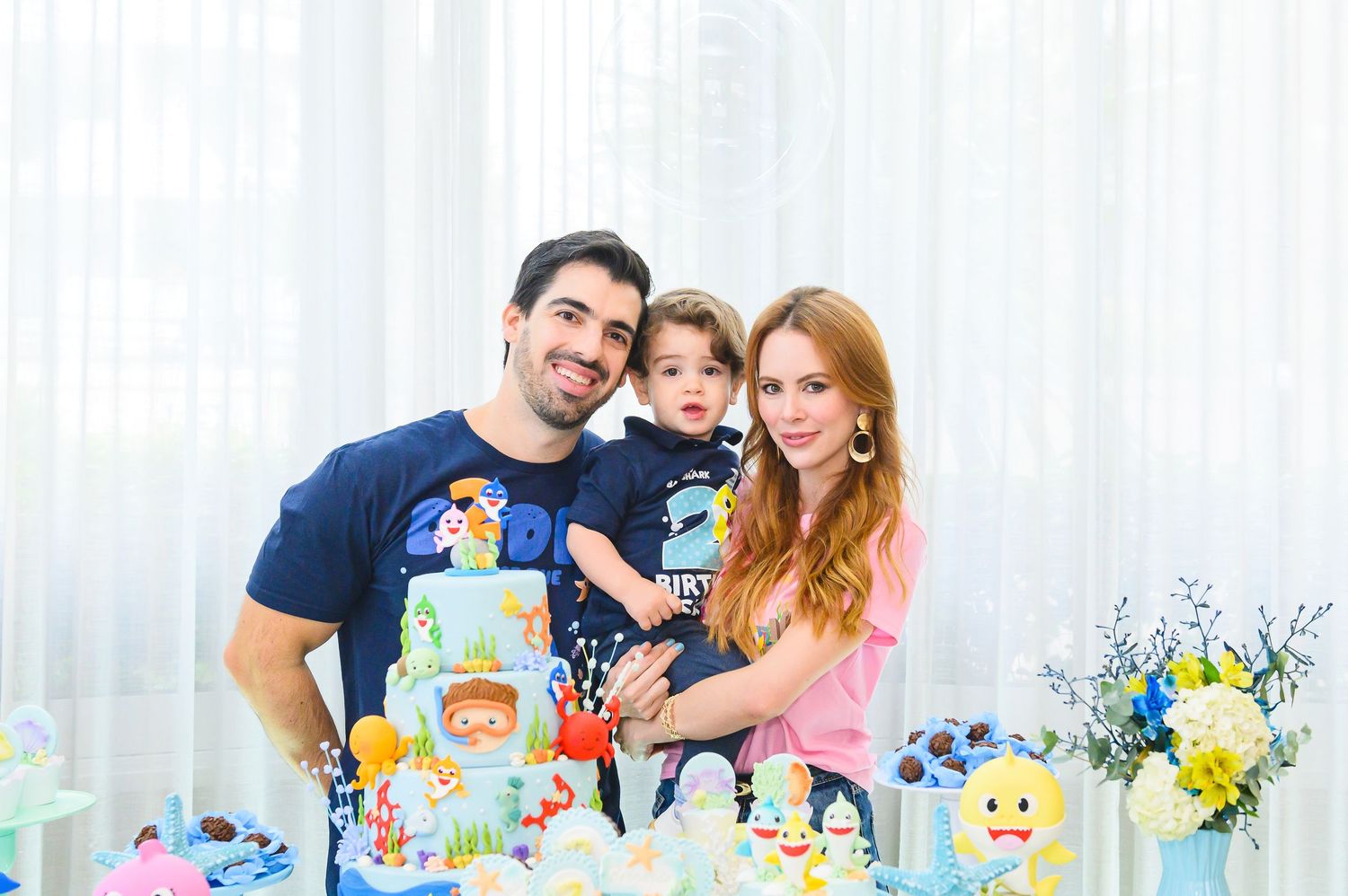 Family having fun at a colorful kids birthday party with cake and decorations around the table.