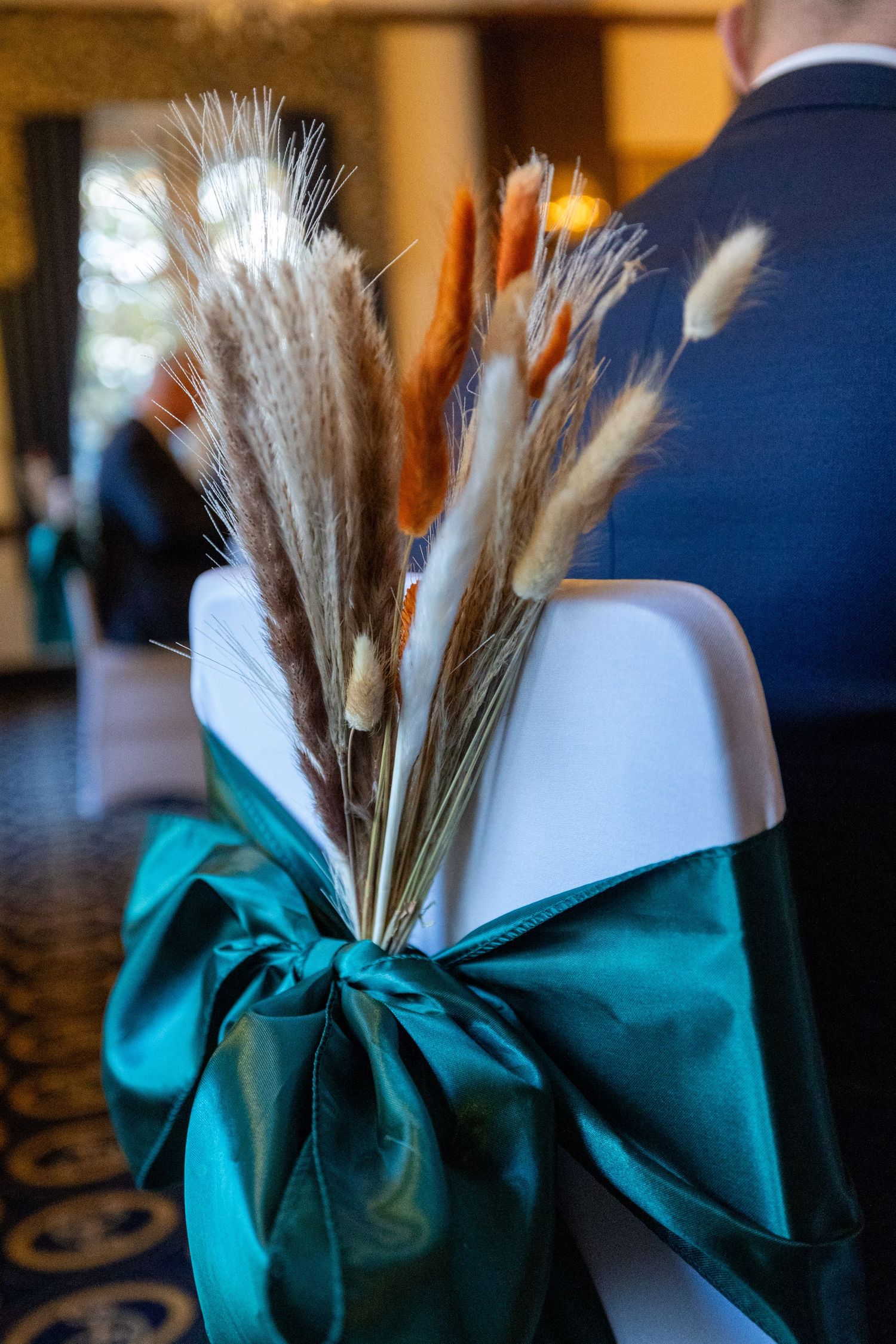ornamental grasses tied tied to the back of a wedding chair with a green sash at the Athenaeum liverpool. Stuart Morris Photography