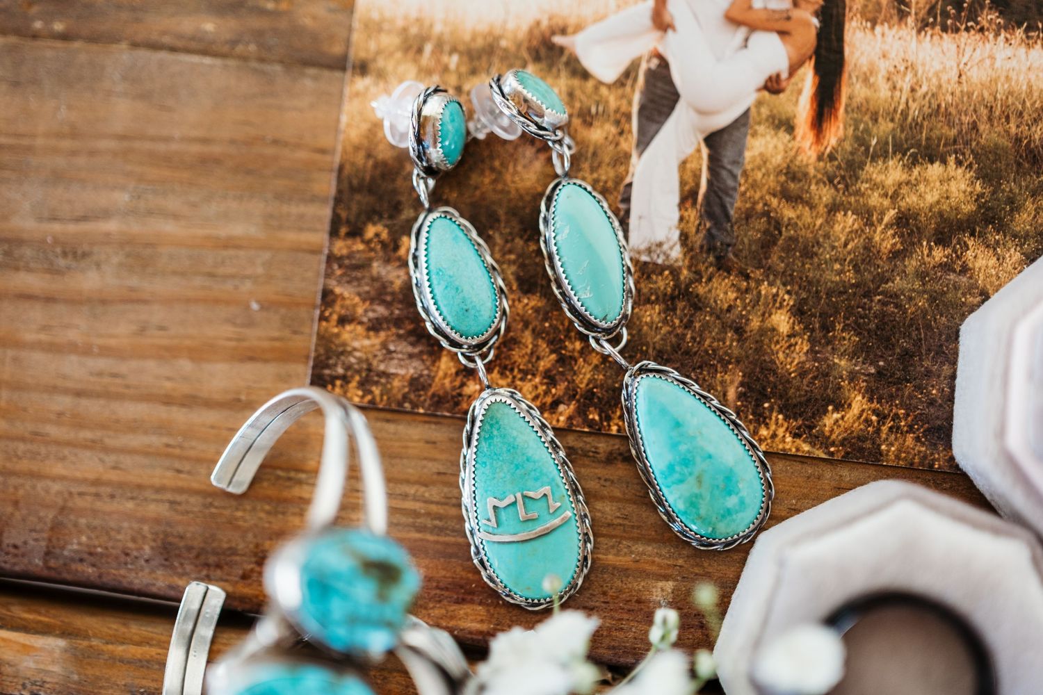 Turquoise and silver southwestern style statement earrings displayed against rustic wooden background.