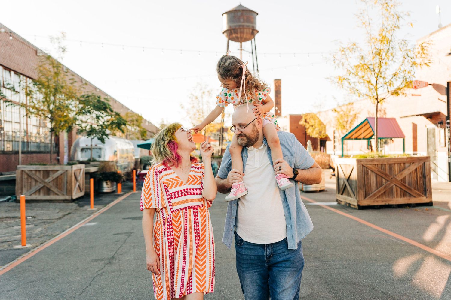 A couple in casual wear walks together through Camp North End during golden hour lighting.