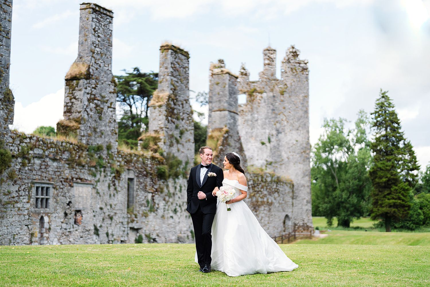 A romantic wedding photography sequence set against the backdrop of historic stone castle ruins in lush green countryside.