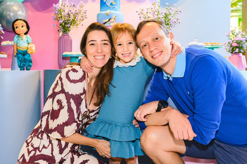 People in coordinating blue and teal outfits smile together in a casual indoor portrait session.