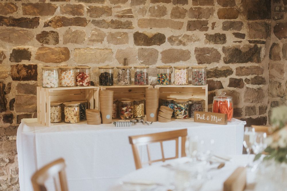 A rustic brick wall interior of a cafe with shelves displaying coffee mugs and supplies.