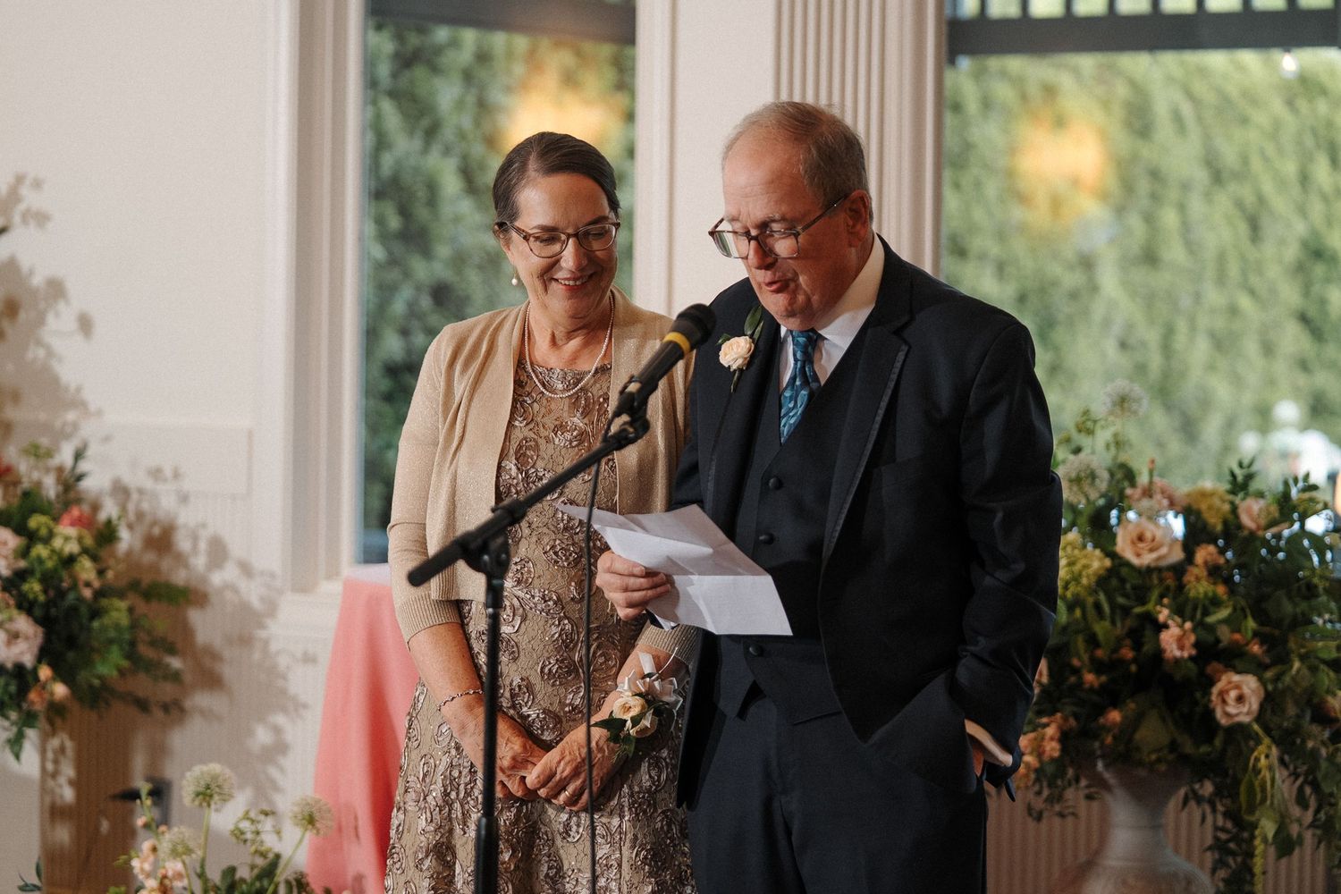 A couple shares joyful moments together at an elegant reception venue decorated with floral arrangements.