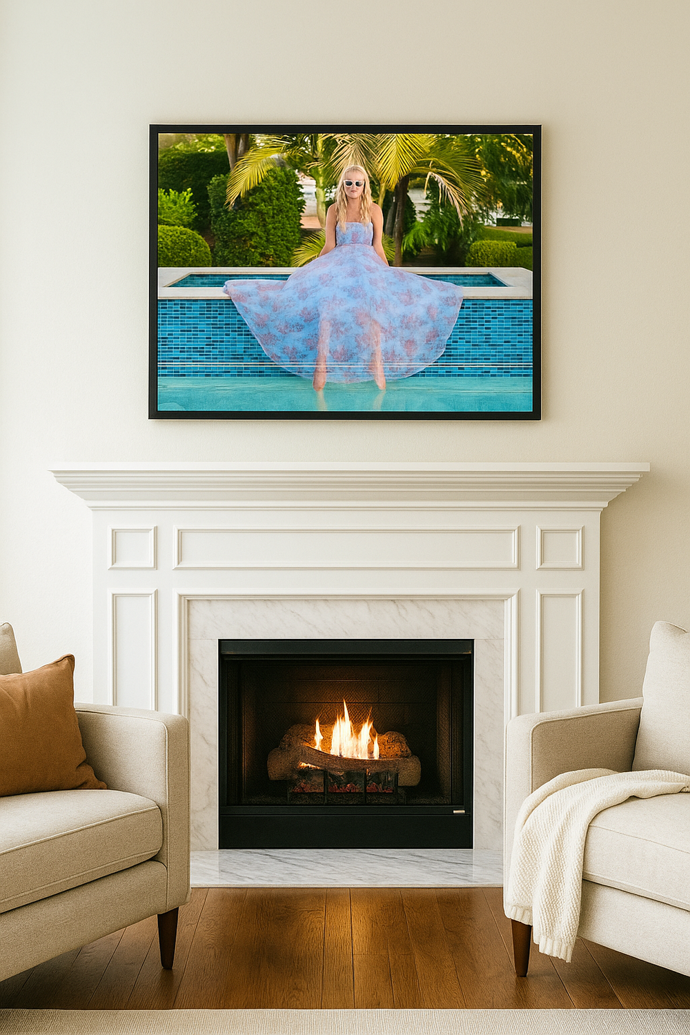 Elegant living room interior with white fireplace, beige armchairs and framed pool photo artwork above mantel.