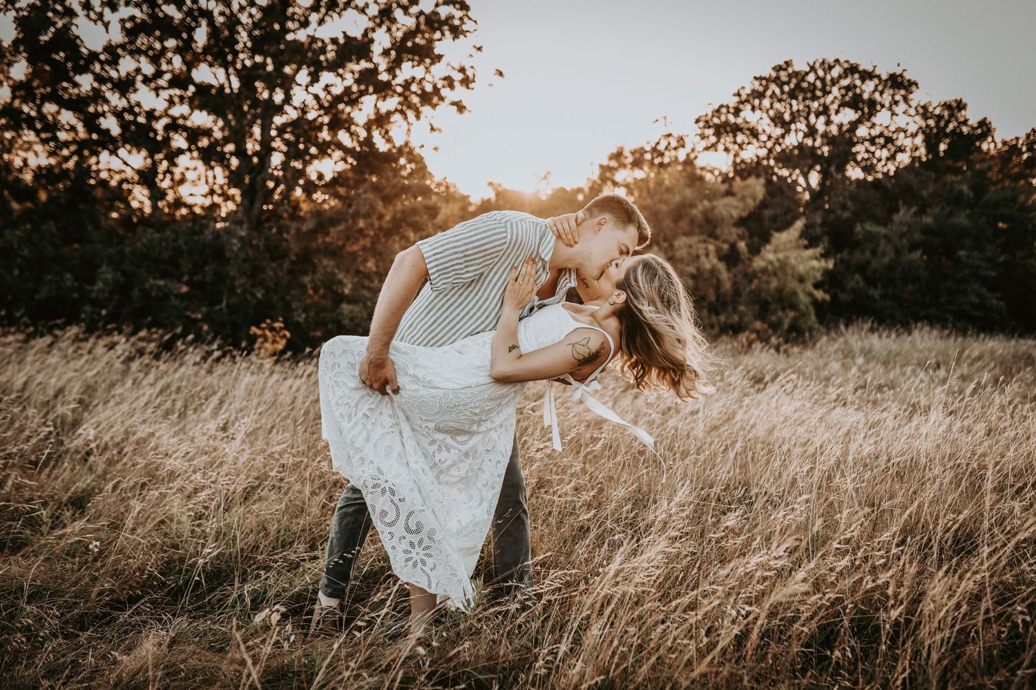 Groom-to-be dipping his fiancée under glowing Texas skies in golden grass