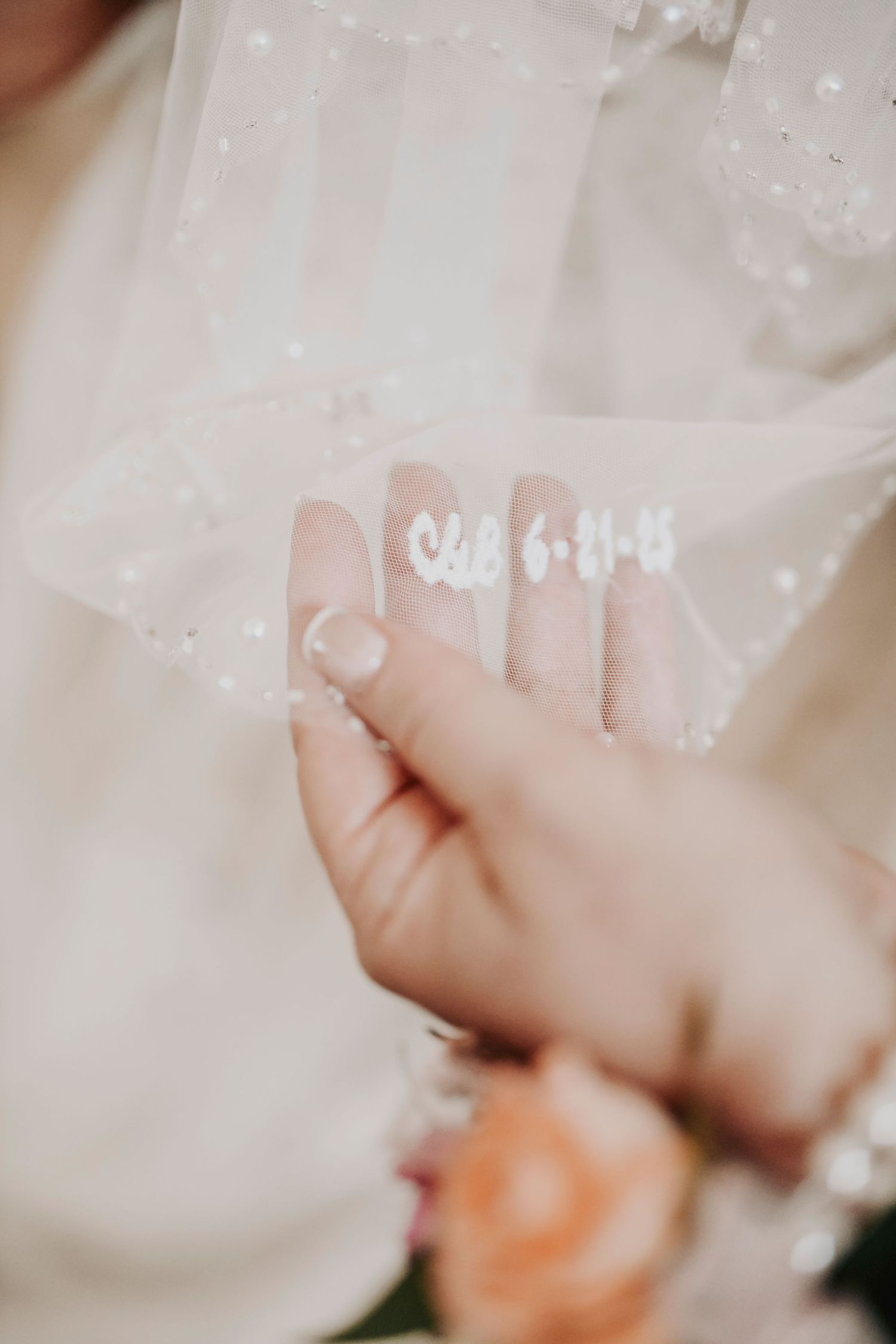 Bride’s veil hanging in soft light with monogrammed wedding date visible