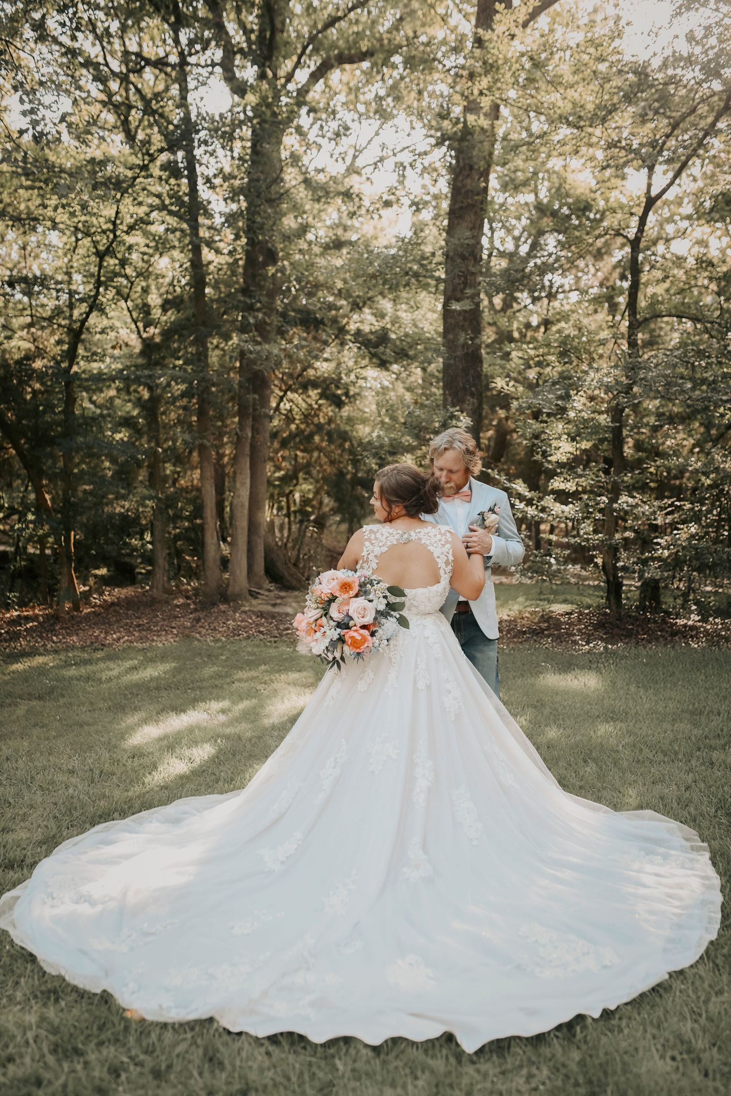 Bride’s gown glowing as the sun sets through the trees behind them