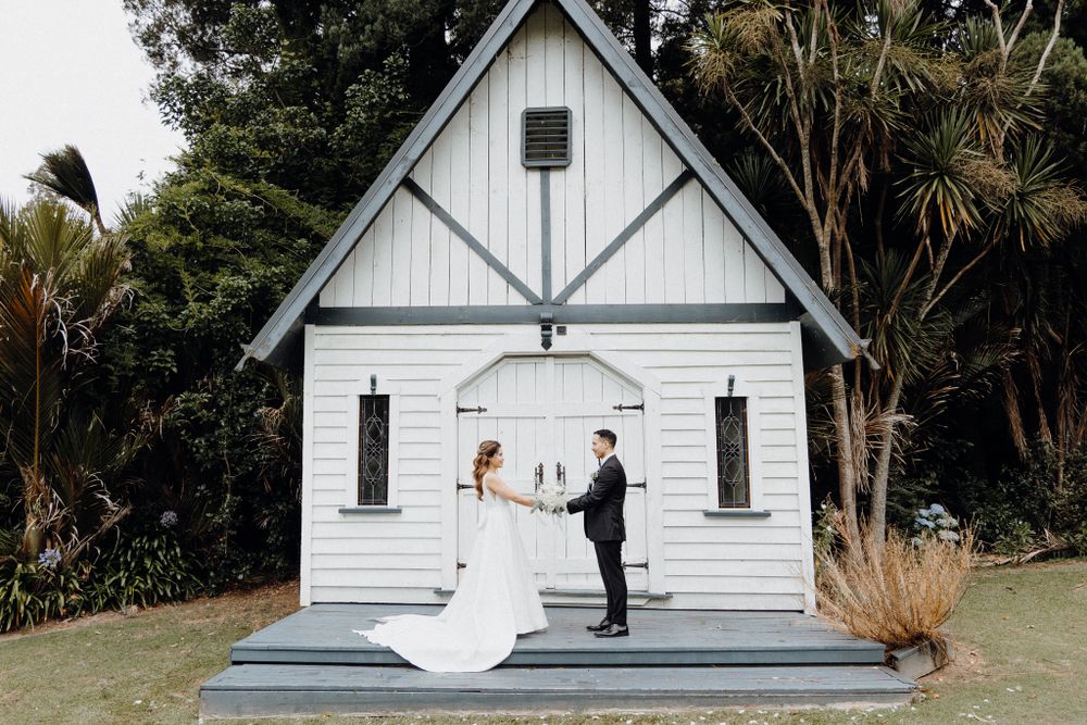 A white chapel wedding ceremony takes place on a small stage captured by Apertured Media Auckland Wedding Photographer.