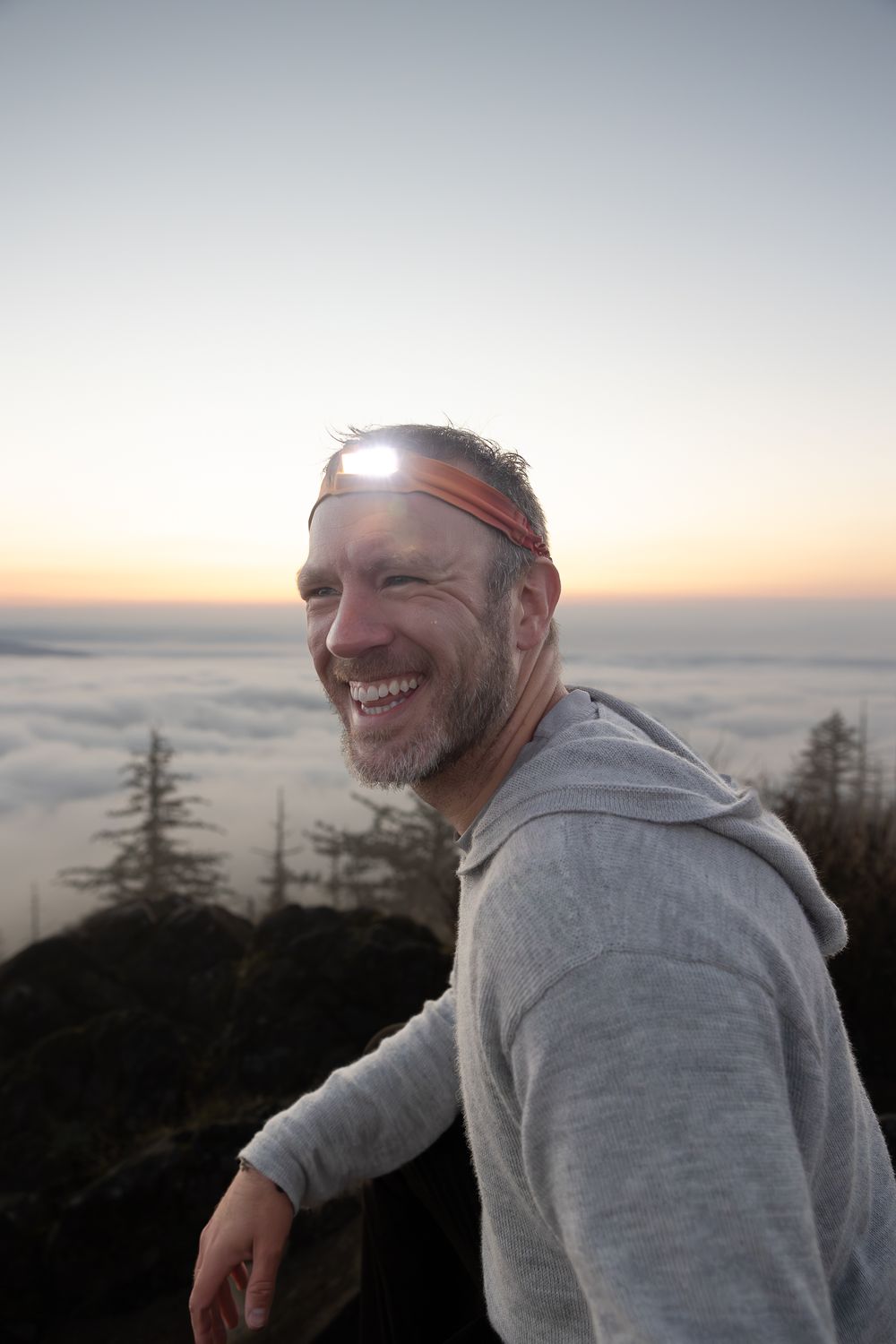 Hiker enjoying the view above the clouds during golden hour on a mountaintop.