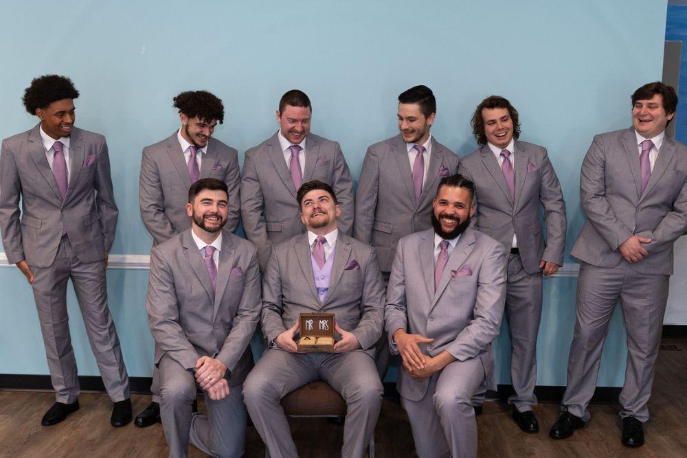 Groomsmen in matching gray suits pose for formal wedding party photo.