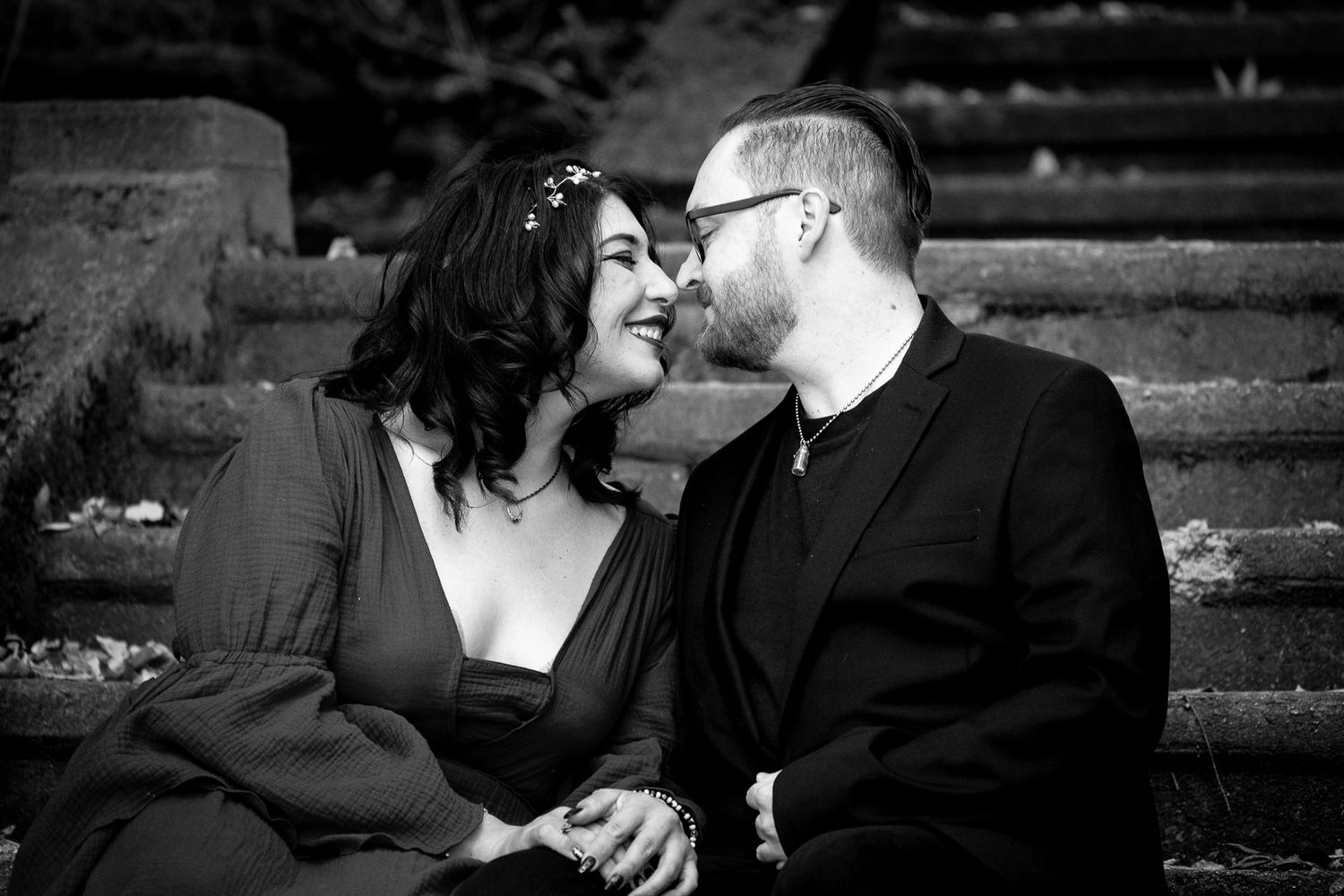 A romantic black and white photo of a couple sharing an intimate moment on stone steps.