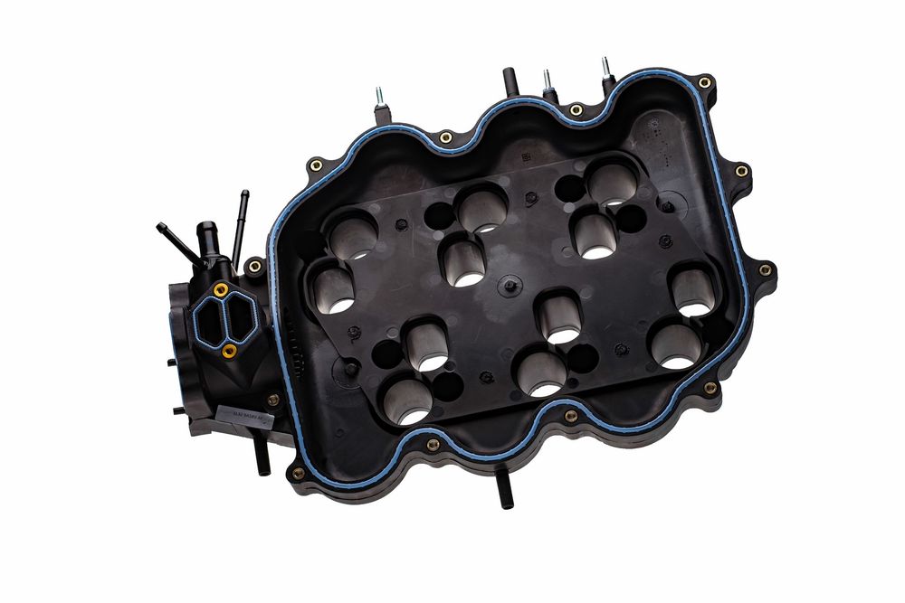 Black plastic automotive engine valve cover with mounting holes and gasket surface isolated on white background.