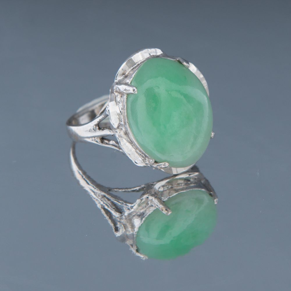 Elegant sterling silver ring featuring a large oval green jade cabochon gemstone with delicate metalwork details.