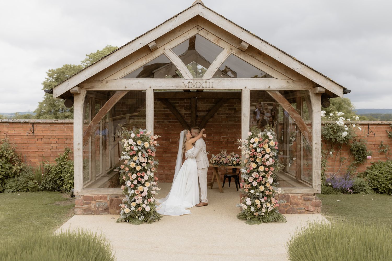 A wedding ceremony setup in a rustic wooden pavilion decorated with floral arrangements and white flowers.