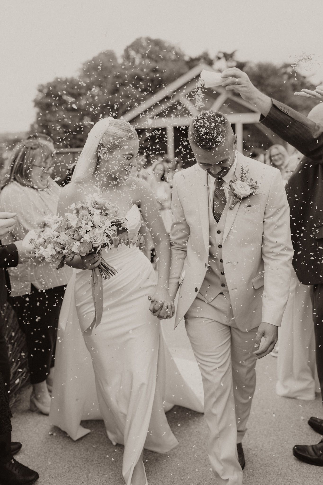 Black and white wedding photo showing celebratory moment with confetti and joy.