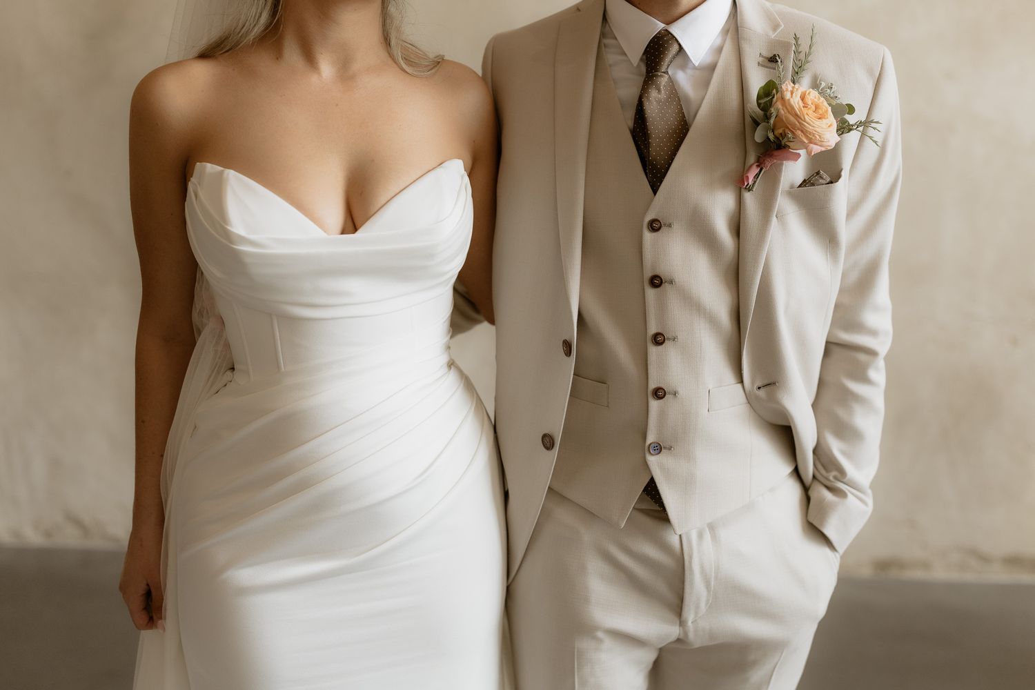 Elegant wedding portrait showing details of classic white dress and beige three-piece suit.
