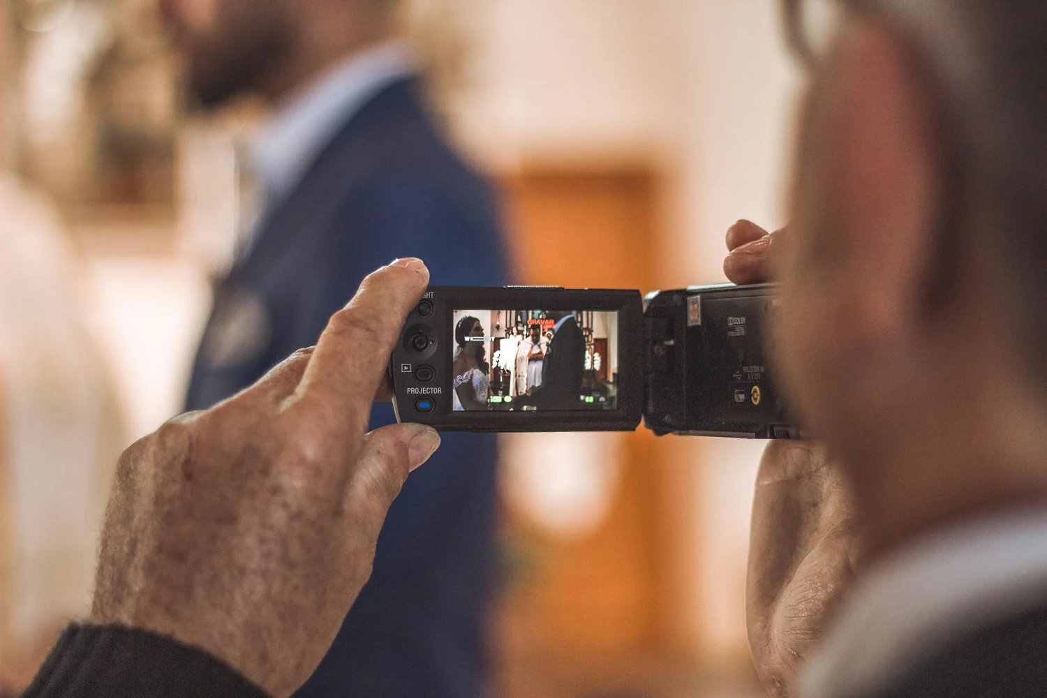 Person taking a photo of a special moment at an event using a smartphone in a blurred indoor setting.