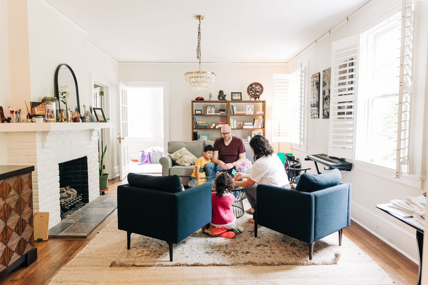People gathered around a circular metal table with a vase of pink flowers having a relaxed social moment together playing UNO in Charlotte