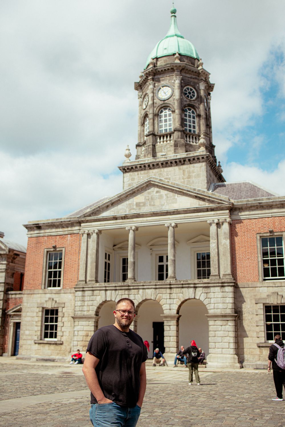 Historic brick building with a clock tower and green dome in Dublin's city center on a cloudy day.