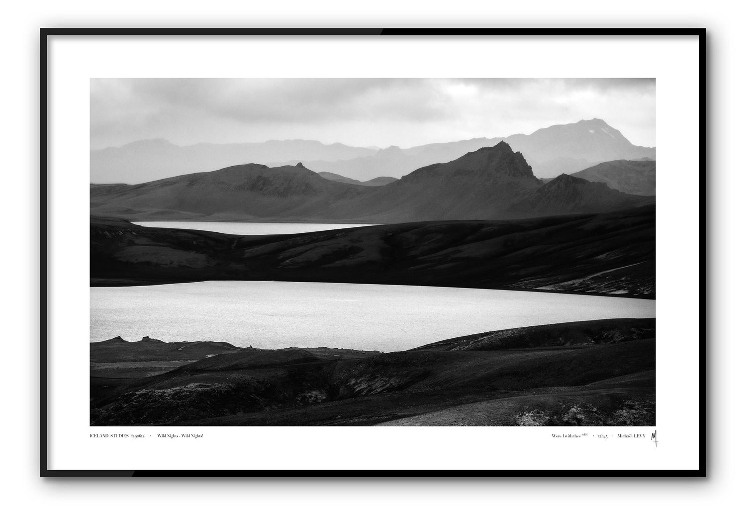 Black and white landscape photograph of rugged mountain peaks overlooking two serene lakes in a remote wilderness setting.