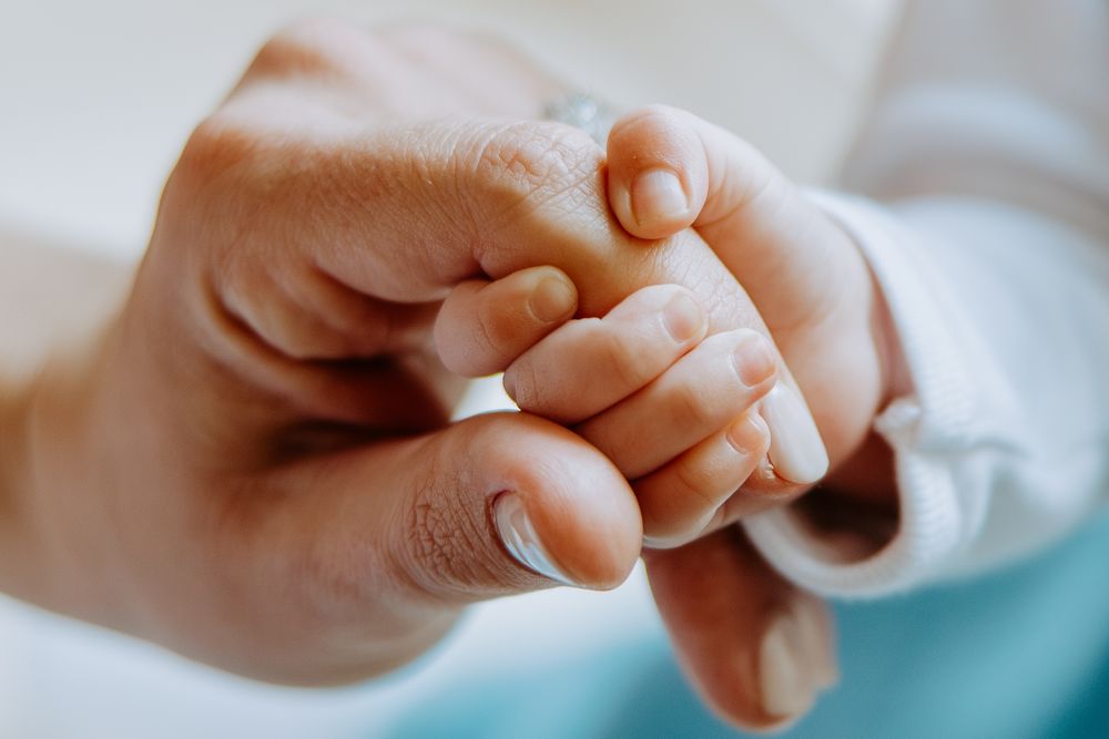 Close-up shot showing hands tenderly holding together in white fabric, capturing an intimate moment of connection.