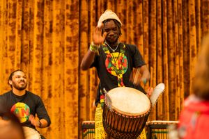 Drummers performing energetic musical number with traditional African drums on stage.