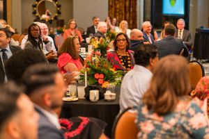 Diverse audience enjoying formal dinner event with festive floral centerpieces.
